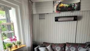 Un salon chaleureux avec un canapé, une table basse et une fenêtre ornée de plantes.