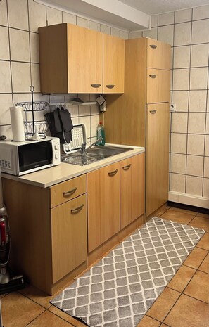 Una cocina con armarios de madera, microondas, tostadora y fregadero.