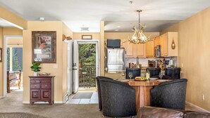 A kitchen with a dining area, a chandelier, and a view through a glass door. - Beaver Lodge — 2BR Frisco Condo, Walk to Lake Dillon, Hot Tub, Sleeps 5 (Frisco)