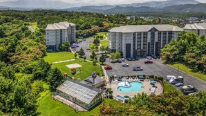 A hotel with multiple buildings, a swimming pool, and a parking lot. - Top Rated Condo | Mtn Views- POOL- Playground (Pigeon Forge)