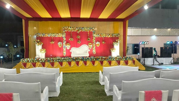 Eine Freilichtbühne mit rotem Hintergrund, weißem Sofa und floralen Dekorationen.