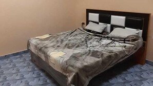 Ein Schlafzimmer mit einem Bett, einem Deckenventilator und einem gemusterten Boden.