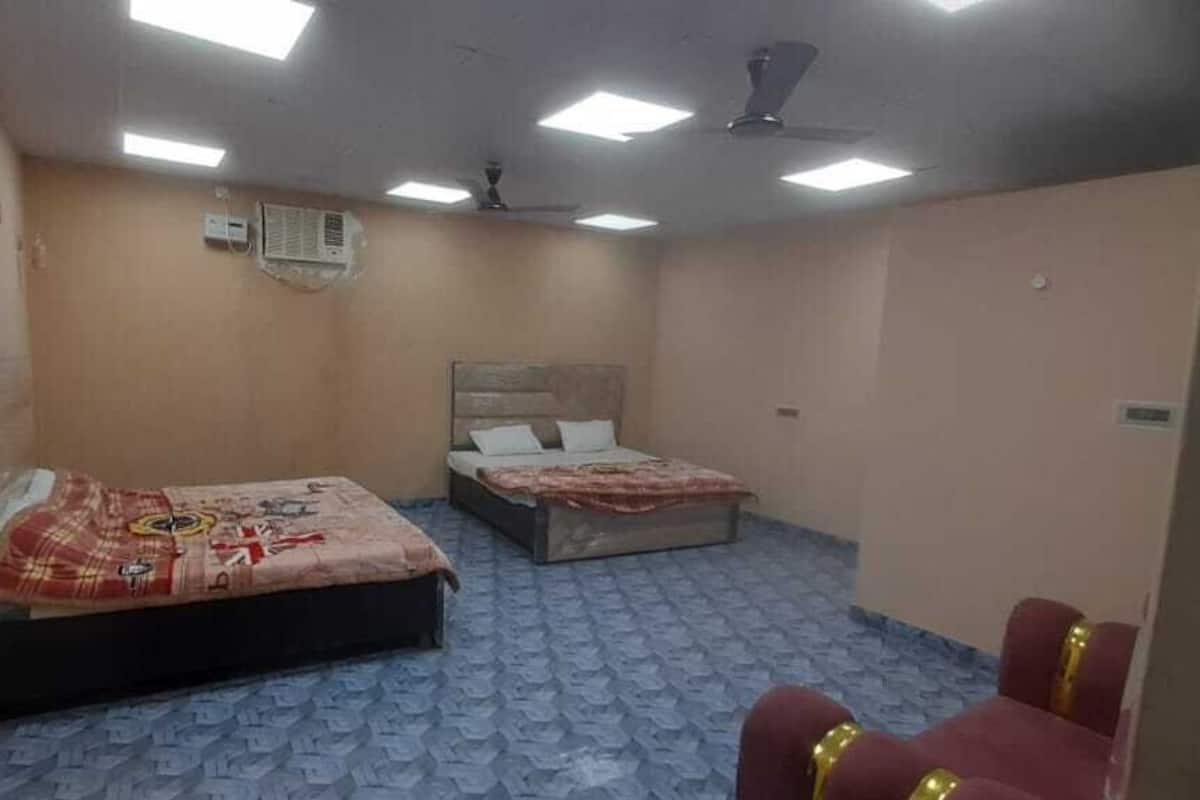 Une chambre d’hôtel avec deux lits, une chaise rouge et un ventilateur de plafond.