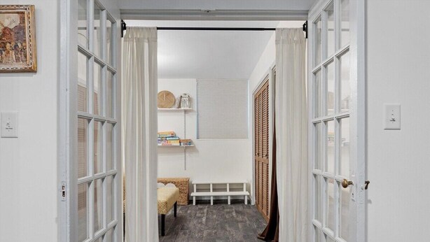 Un couloir étroit avec un banc, un lit et une étagère contenant des livres et une horloge.