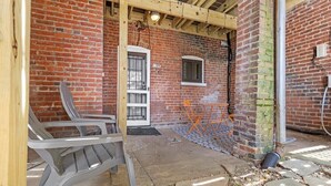 Un bâtiment en briques avec une structure en poutres de bois, une porte et une petite fenêtre.
