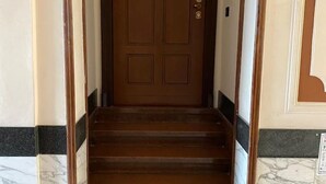 Eine Holztreppe führt zu einer braunen Tür mit Schlüsselloch und Schloss.