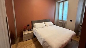 Ein Schlafzimmer mit Bett, Nachttisch und Fenster.