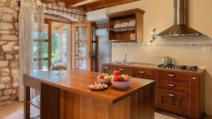 A kitchen with a wooden island, stone walls, and a large window.