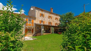 A stone building with a covered patio and a grassy lawn.