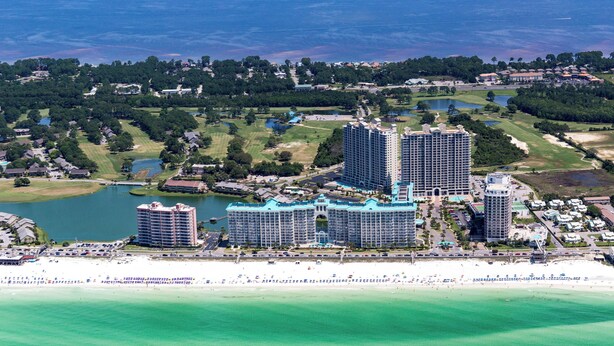 A coastal resort with multiple high-rise buildings, a beachfront, and surrounding greenery.