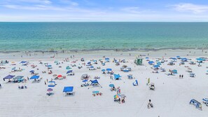 Une plage dotée de nombreux parasols et de chaises longues, d’une tour de surveillance pour les sauveteurs, et offrant une vue dégagée sur l’océan.