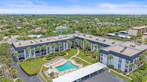 Un hôtel moderne doté d’une piscine sur le toit, entouré d’une végétation luxuriante et offrant une vue dégagée sur le paysage urbain.