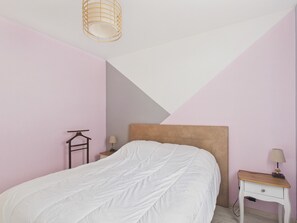 Quarto com cama, mesa de cabeceira, luminária e luminária pendente.