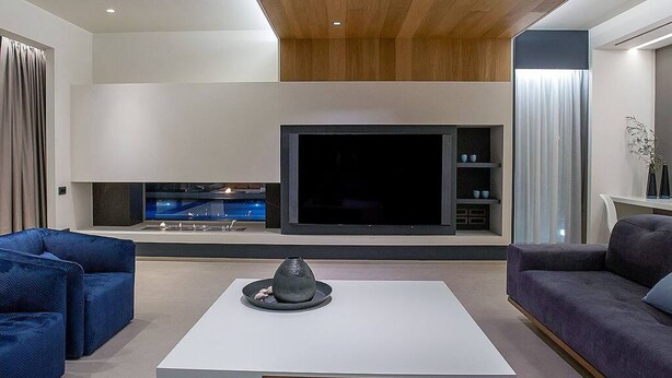 A modern living room with a large flat-screen TV, two sofas, and a coffee table.