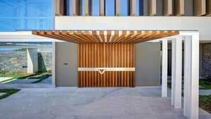 A modern building with a wooden slatted entrance, a stone wall, and a clear sky.