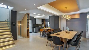 A modern kitchen with a dining area, featuring a wooden dining table, black chairs, and a unique chandelier.