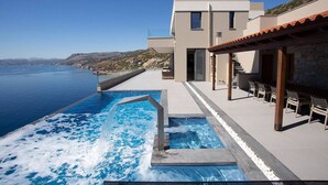 A modern building with a pool overlooking a body of water.