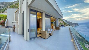 A modern house with a glass balcony overlooking the sea.