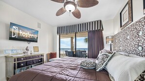 Une chambre dotée d’un grand lit, d’un ventilateur de plafond, d’un téléviseur diffusant « hosteeva », d’une commode et offrant une vue sur l’extérieur.