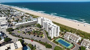 A coastal residential area with a beachfront, a parking lot, and a tennis court.