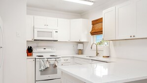 Eine moderne Küche mit weißen Schränken, einer eingebauten Mikrowelle, einem Backofen und einem Spülbecken.