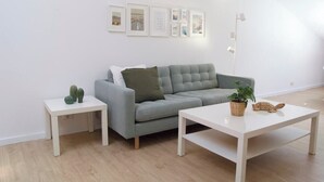 Una sala moderna con un sofá gris, una mesa de centro blanca y una mesita auxiliar con un cactus.