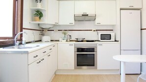 Cocina compacta con alacenas blancas, microondas, estufa y refrigerador.