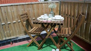 Una mesa de madera con sillas, un jarrón y una pequeña disposición para servir.