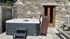 Ein Steinhaus mit einer Holztür, einem Whirlpool und einer überdachten Bank.