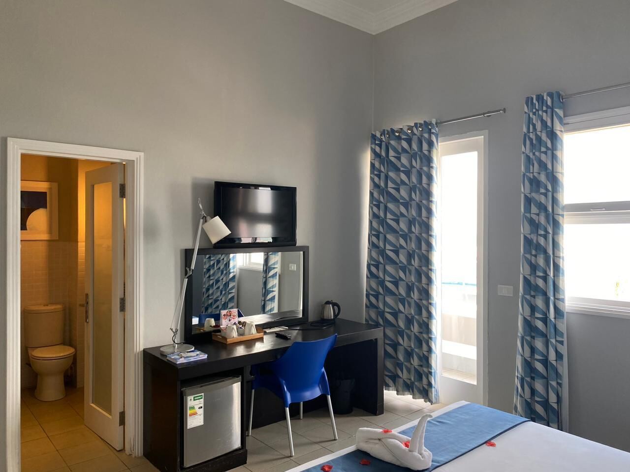 A compact hotel room with a desk, chair, and a bed.