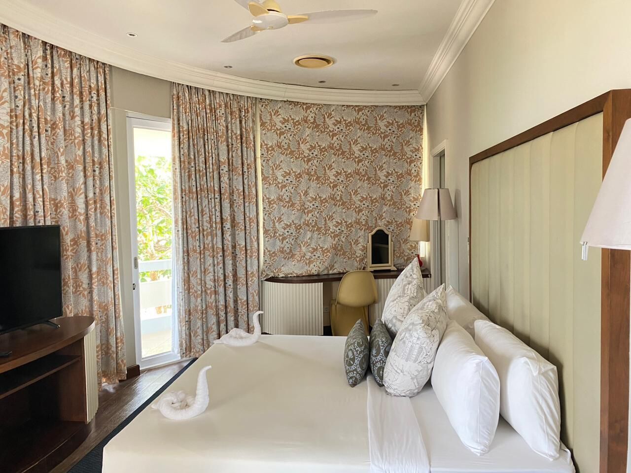 Una camera d'albergo con un letto, una televisione, una scrivania e una sedia.