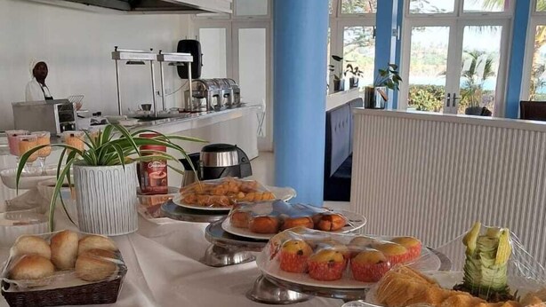 A buffet table with various food items, including pastries, fruits, and beverages. - Dona Ana Hotel (Vilanculos)