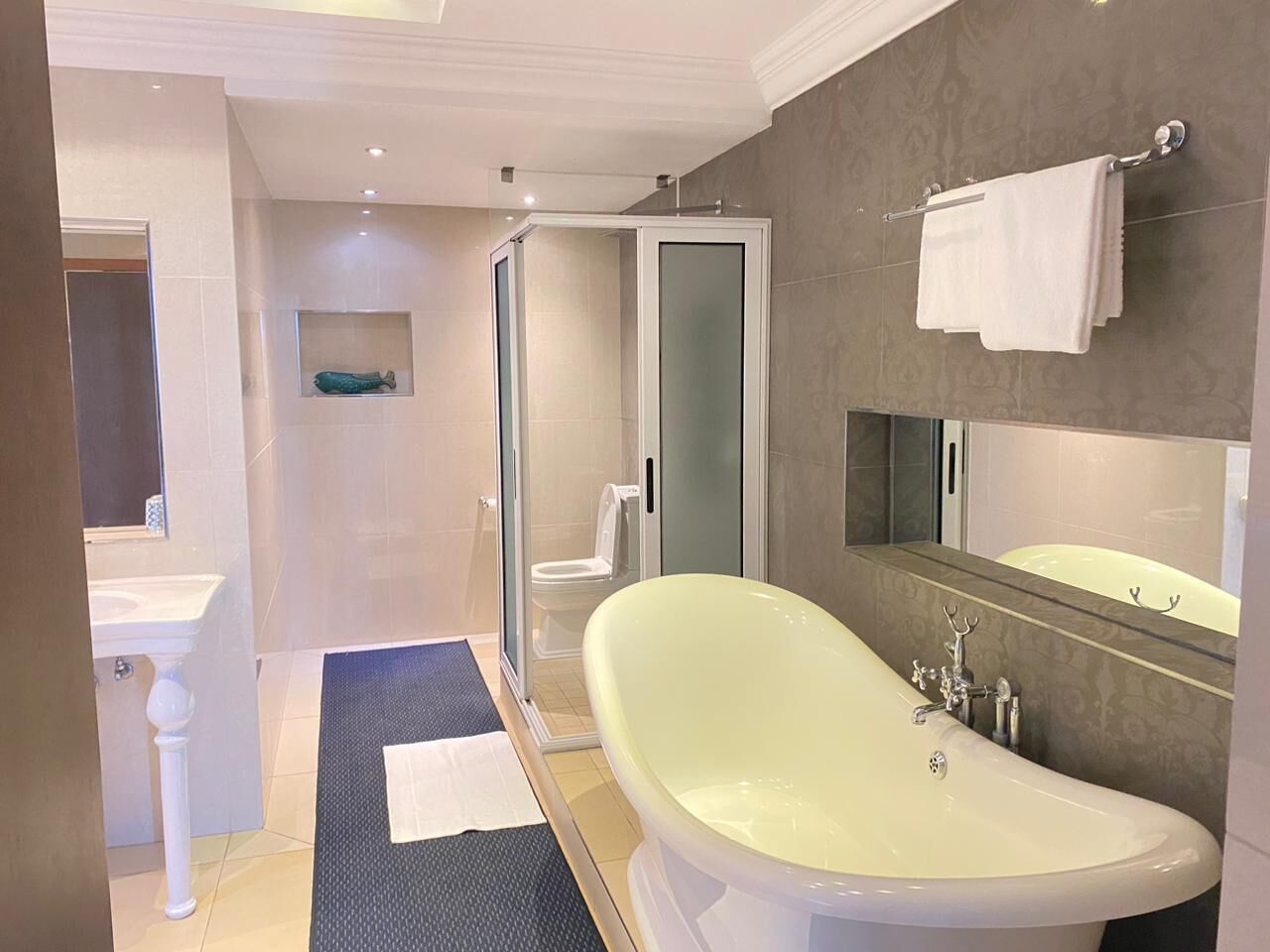 Un baño moderno con una bañera independiente, una ducha con cerramiento de vidrio y un espejo grande sobre el lavamanos.