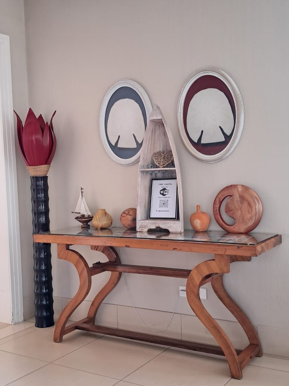 A wooden table with a unique design, a vase, and two wall-mounted circular mirrors.