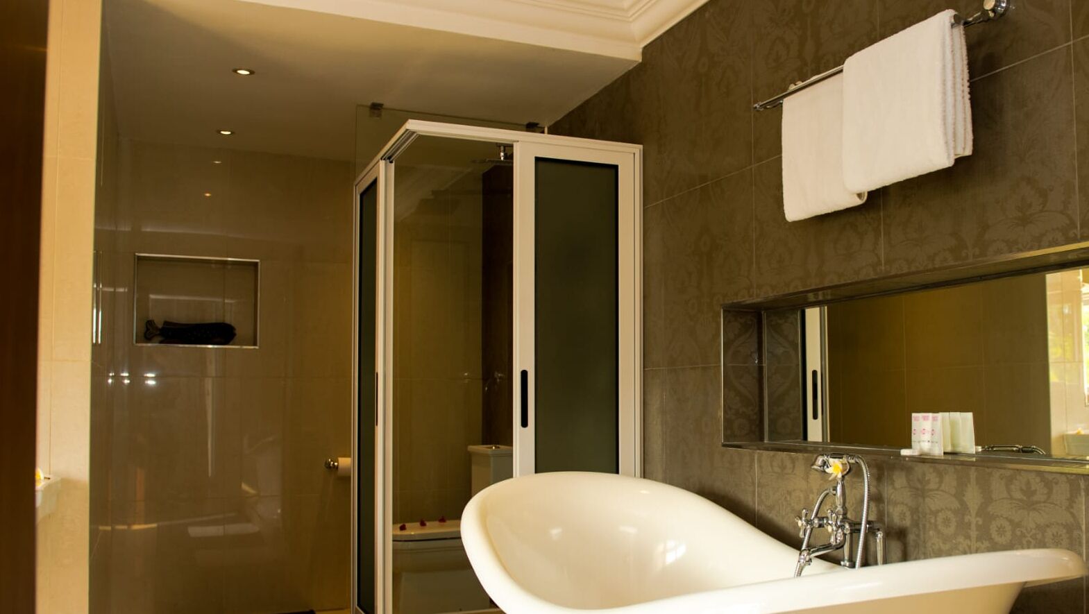 Un baño moderno con una bañera independiente, ducha con mampara de vidrio y un espejo grande sobre el lavabo.