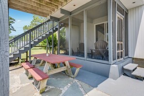 A covered patio with a wooden table and benches, a staircase, and a view of the backyard. - The Virginia Lee by Seaside Vacations & Sales (Chincoteague Island)