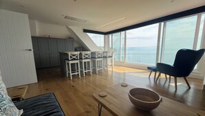 A modern living space with a kitchen, dining area, and a large window overlooking the sea. - Relaxing penthouse break overlooking the sea with a 150m to the sandy beach (Swanage)