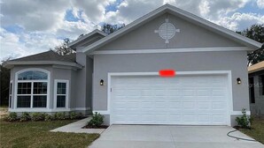 Ein Wohnhaus mit Garage, Auffahrt und einem angelegten Rasen.
