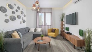 A modern living room with a grey sofa, a yellow armchair, a wooden coffee table, and a TV mounted on the wall.