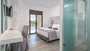 A modern hotel room with a bed, a desk, a chair, and a glass door leading to a balcony.