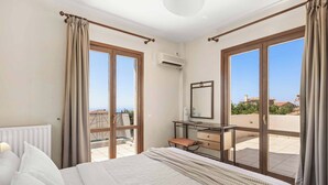 Un dormitorio con una cama grande, un aparador, un espejo y vistas al exterior.