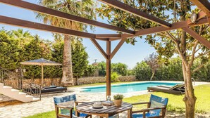 Un patio cubierto con piscina, mobiliario exterior y un sendero de piedra.