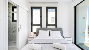 Ein modernes Schlafzimmer mit einem großen Bett, zwei Nachttischen, einem begehbaren Kleiderschrank und einer Schiebetür nach draußen.