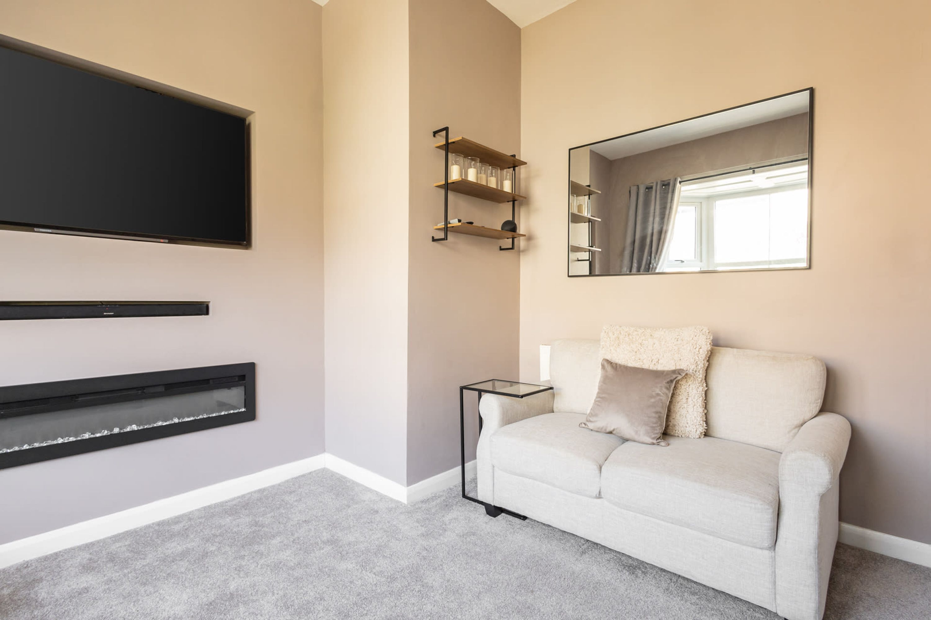 Una sala moderna con televisión de pantalla plana, chimenea, sofá y espejo.
