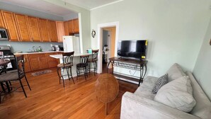 A living room with a sofa, a TV, and a dining area with chairs and a table. - Huge 3 Bedrooms Apt 15 Minutes to NY City (West New York)