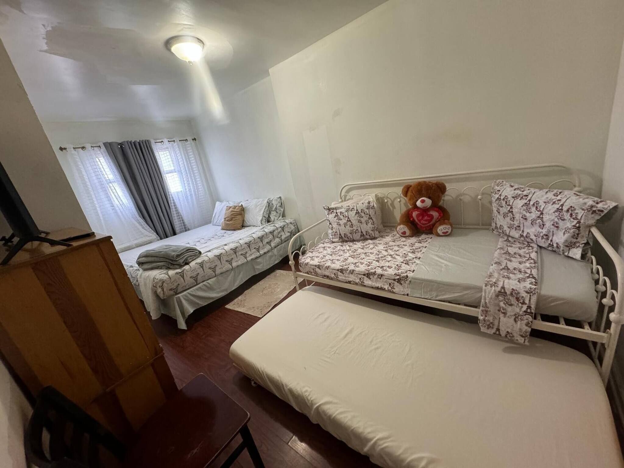 A bedroom with two beds, a desk, and a chair.