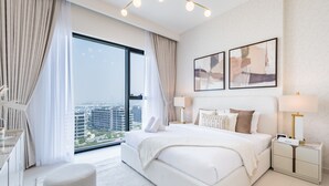 Una habitación de hotel moderna con una cama grande, mesitas de noche, vistas de la ciudad y arte abstracto en la pared.