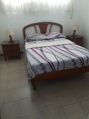Cozy bedroom with a single bed, two nightstands, and a window with sheer curtains.