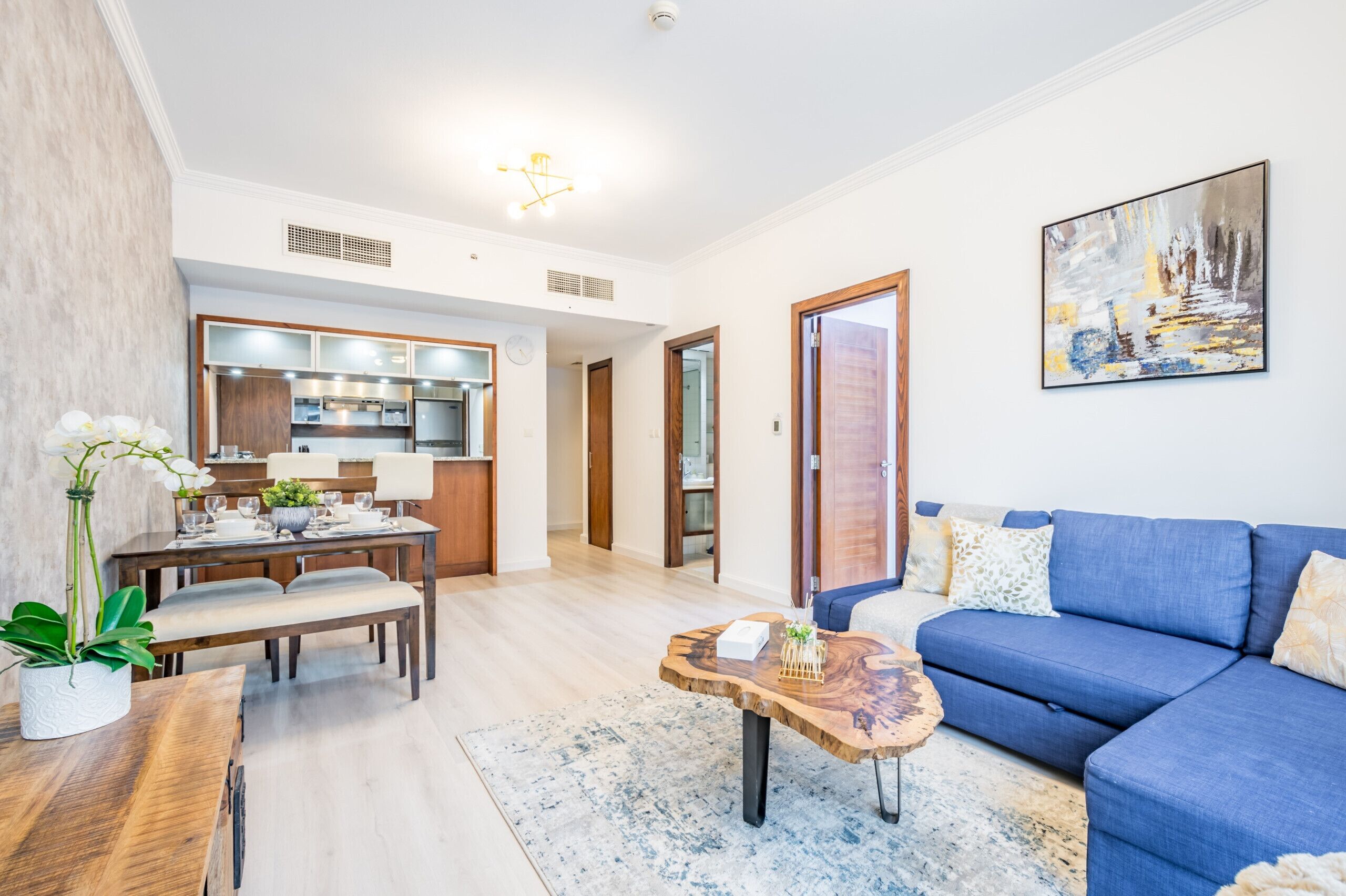 Un soggiorno moderno con un divano blu, un tavolo da pranzo in legno e una cucina sullo sfondo.