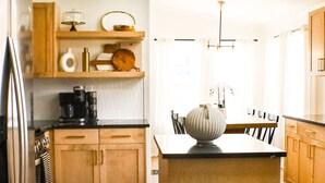 A modern kitchen with wooden cabinets, a black countertop, and a central island. - Trail Chaser Moab, UT (Moab)